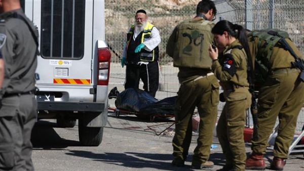 Israeli forces stand next to the body of a Palestinian who was shot dead following an alleged attempt to stab Israeli border police, at a checkpoint near the Israeli settlement of Har Homa in the occupied West Bank, on February 14, 2016. (AFP/File)