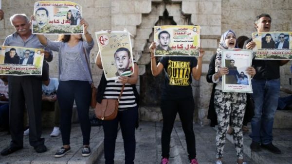 Palestinian protesters hold posters during a demonstration against administrative detention and in support of Palestinian prisoner Bilal Kayed (portraits) on August 24, 2016 at Damascus Gate, a main entrance to Jerusalem's Old City. (AFP/Ahmad Gharabli)