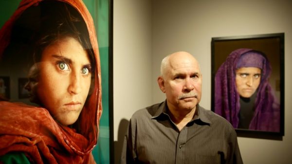 Ulrich Perrey US photographer Steve McCurry poses next to his photos of the "Afghan Girl" named Sharbat Gula. (AFP/File)