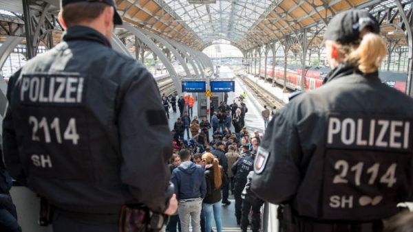 Policemen look at a group of refugees waiting on a platform of the main station in Munich, Germany. (AFP/File)