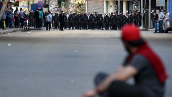 A protester sits in front of riot policemen during a demonstration on April 15, 2016 in central Cairo against a controversial deal to hand two islands in the Red Sea to Saudi Arabia. (AFP/Mohamed El-Shahed)