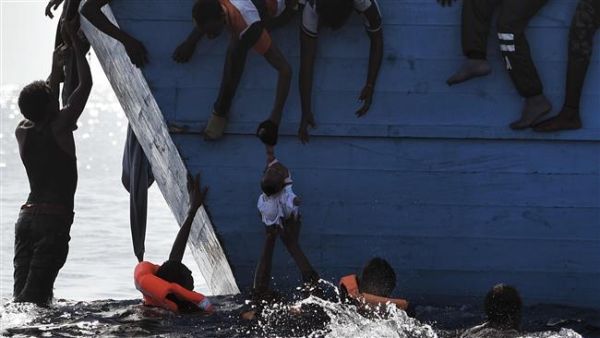 Refugees try to pull a child out of the water as they wait to be rescued by members of Proactiva Open Arms NGO in the Mediterranean sea, some 12 nautical miles north of Libya, on October 4, 2016. (AFP/File)