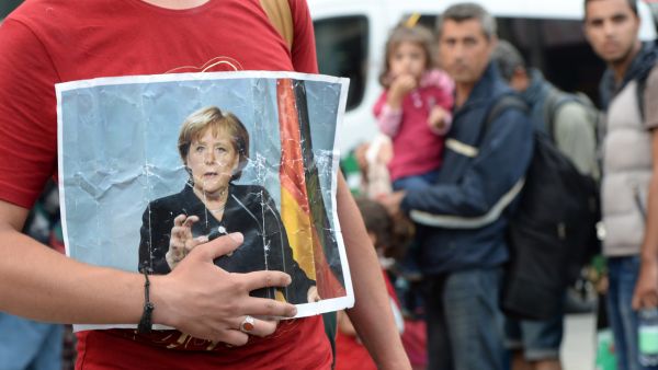 A refugee holds a picture of German Chancellor Angela Merkel as refugees arrive at the main station of Munich. (AFP/File)
