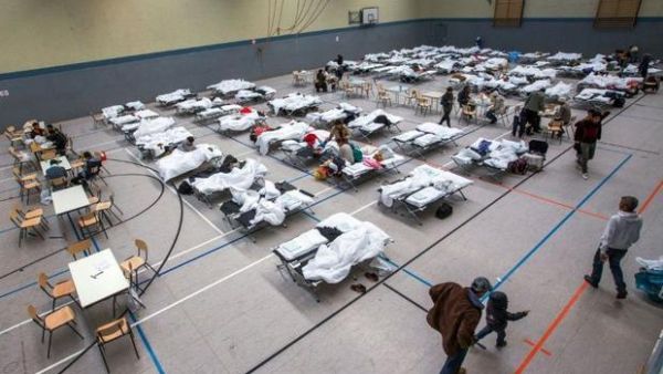Migrants walk next to camp beds in a makeshift refugee shelter in a gym in Stern, Germany. (AFP/File)