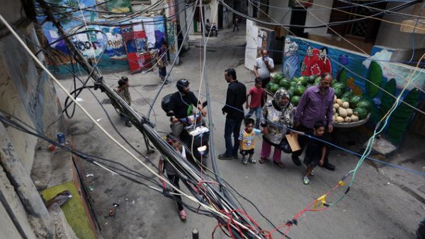 In this May 21, 2014 photo, Palestinian refugees walk under electricity cables in an alley in the Palestinian refugee camp of Shatila in Beirut, Lebanon. (AFP/Bilal Hussein)