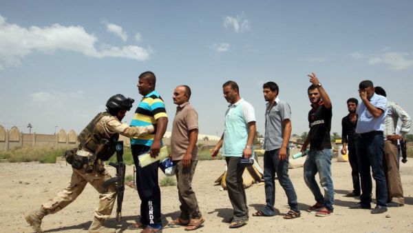 An Iraqi soldier bodychecks men in Baghdad as they arrive to volunteer to join the fight against a major offensive by jihadists in northern Iraq on June 13, 2014. Iraqi forces have clashed with militants advancing on the city of Baquba, just 60 kilometres north of Baghdad. (AFP/Ali Al Saadi)