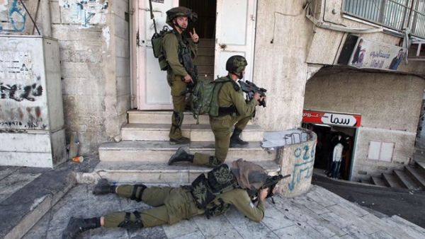 Israeli soldiers aim their guns at Palestinian youths during clashes in Hebron on October 4, 2015.  (AFP/Hazem Bader)