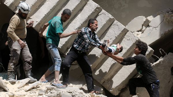 Syrians evacuate a toddler from a destroyed building following a reported air strike on the rebel-held neighbourhood of al-Kalasa in the northern Syrian city of Aleppo, on April 28, 2016. (AFP/File)