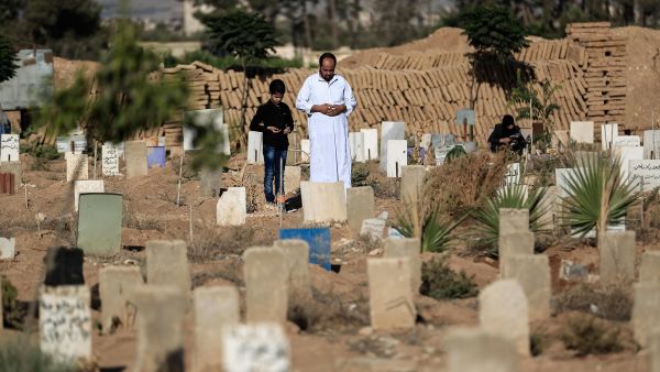A Syrian man and his son pray over the grave of a relative at a cemetery. (AFP/File)