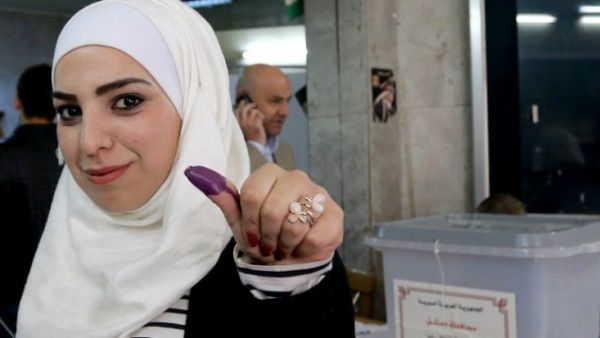 A Syrian woman shows her ink stained thumb after voting at a polling station during parliamentary. (AFP/File)