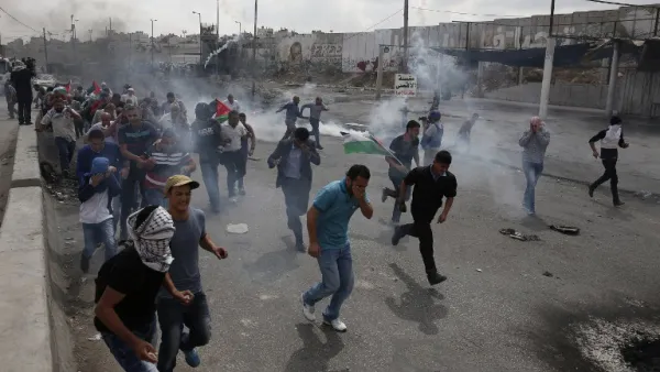 Palestinians run from tear gas smoke during clashes with Israeli security forces at the Qalandiya checkpoint. (AFP/File)