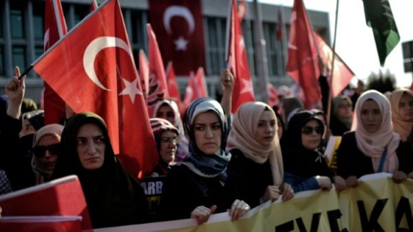 A group of women holds a banner as Pro-Erdogan protesters wave Turkish flags. (AFP/File)