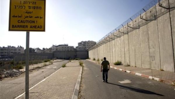 فلسطيني يمشي بجانب جدار العزل في بيت حنينا شرق القدس/أ.ف.ب