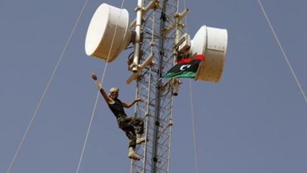 مقاتل من المناوئين للقذافي يشير بعلامة النصر بعد ان رفع علم المجلس الوطني الانتقالي على برج للاتصالات في بلدة تبعد 15 كيلومترا شمالي بني وليد 