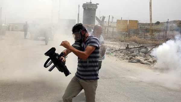 Palestinian journalists run for cover from tear gas canisters fired by Israeli forces during a demonstration in support of Palestinian journalists on the occasion of the World Press Freedom day. (AFP/File) 