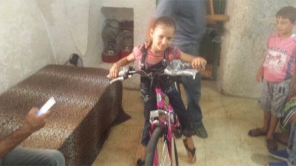 Anwar Burqan is seen smiling with her new bicycle gifted to her by Sami Jolles. (Twitter)