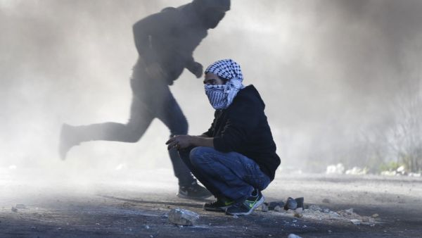 Palestinian protesters clash with Israeli troops near an Israeli checkpoint in the West Bank city of Ramallah on December 8, 2017 (Abbas Momani/AFP)
