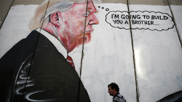 A Palestinian man walks past graffiti depicting US President Donald Trump on the controversial Israeli separation wall in the West Bank town of Bethlehem. (AFP) 