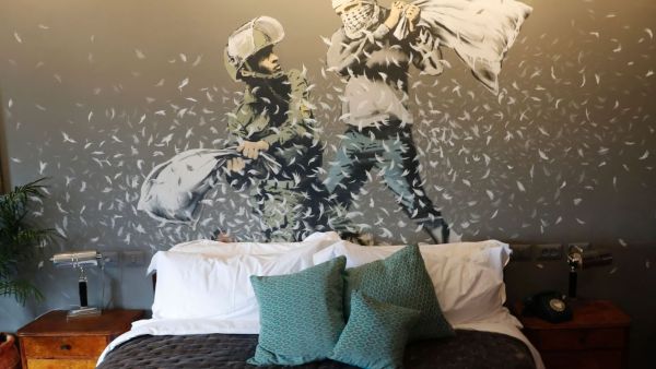 A picture shows a bed and graffiti inside street artist Banksy's newly opened Walled Off hotel in the Israeli occupied West Bank town of Bethlehem, on March 3, 2017. (AFP/Thomas Coex) 