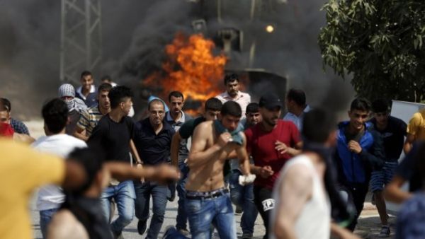 Palestinian youths run from the path of an Israeli army bulldozer during clashes in the village of Koubar, west of Ramallah, on July 22, 2017, as Israeli forces try to close the roads leading to the village. (AFP/ Abbas Momani)