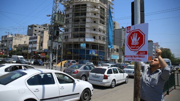 A Palestinian man hangs on May 22, 2017 in Gaza City a traffic sing with Arabic writing on reading "stand with our prisoners'' in solidarity with Palestinian hunger-striking prisoners in Israeli jails. (AFP/Mohammed Abed)