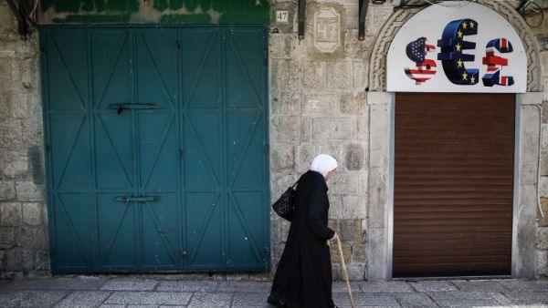 An elderly woman walks past closed shops in the Old City of Jerusalem on April 27, 2017, during a trade strike in support of Palestinian prisoners on hunger strike in Israeli jails. (AFP/Ahmad Gharabli)