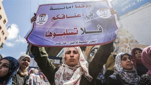 A woman holds a sign reading 'We trust you with our rights, please do not rob them' during a demonstration by UNRWA employees. (Mahmud Hams/AFP)