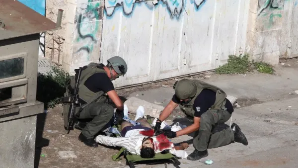 Israeli security forces inspect the body of a Palestinian man who stabbed and lightly wounded an Israeli border guard before being shot dead in the Israeli occupied West Bank city of Hebron, on October 29, 2015. (AFP / Hazem Bader)  