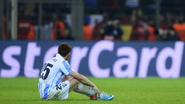 Malaga player slumps after the controversial Champions League defeat (AFP/John MacDougall)