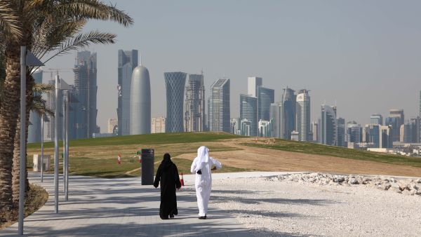 Arabic couple walking in front of the Doha downtown skyline. (Shutterstock/Philip Lange)