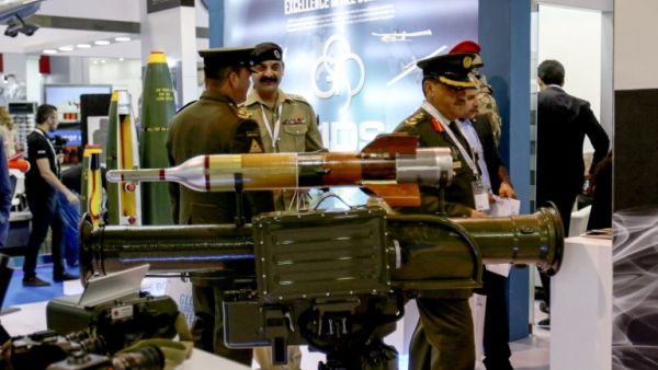 Uniformed visitors walk past a rocket-propelled grenade launcher on display /AFP