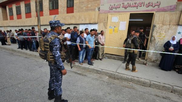 Members of the Iraqi security forces stand guard as people queue in front of a polling station in the Wadi Hajar district of Mosul on May 12 /AFP