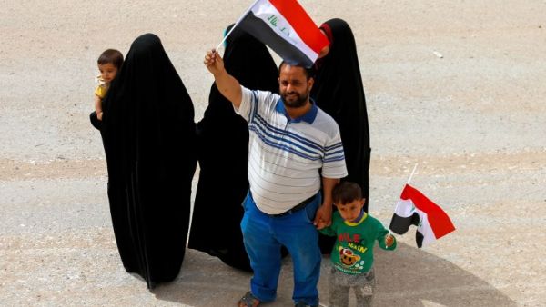 An Iraqi man and a child wave the national flag in the central holy city of Najaf on May 12, 2018 as the country votes in the first parliamentary election since declaring victory over ISIS. (AFP/File Photo)