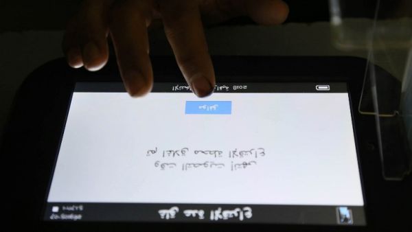 A voting official checks the message on the voting machine, which reads in Arabic "Voting time is over, the station is now closed" /AFP