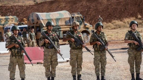 Turkish soldiers stand near armored vehicles near the Turkey-Syria border. (Ilyas Akengin/AFP)