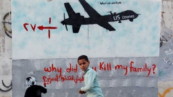 Yemeni boy walk past a mural depicting a U.S. drone, which reads, "Why did you kill my family," in the capital Sanaa. (AFP/ File)