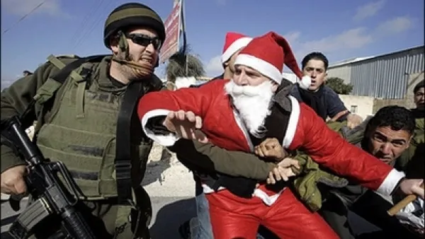 An Israeli soldier tackles a Palestinian protester dressed as Santa Claus or Father Christmas during at a protest against Israel’s separation barrier in the village of Umm Salamunah near the biblical West Bank town of Bethlehem. Israeli guards beat five demonstrators during the protest on Friday, organisers said.
Dec. 23, 2007 (AFP/Musa al-Shaer)