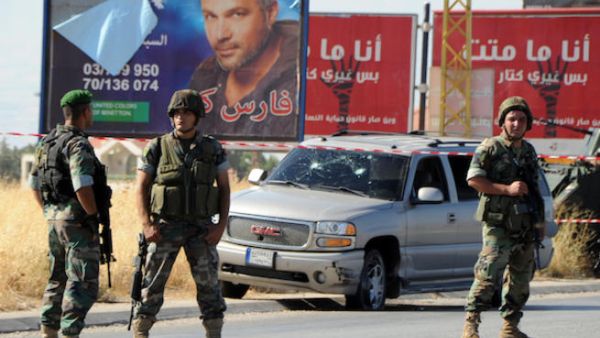 Lebanese soldiers stand guard at the site of a car bomb attack that hit a Hezbollah convoy travelling towards the Lebanese border crossing with Syria, on the Majdal Anjar-Masnaa road on July 16, 2013. (Source: AFP/STR)