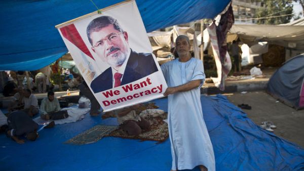 An Egyptian holds a portrait of deposed president Mohamed Morsi during a continiuing sit-in in his support outside Rabaa al-Adawiya mosque in Cairo (AFP/KHALED DESOUKI)