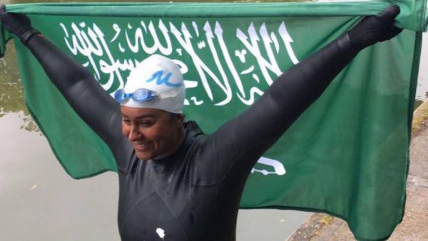 Mariam Binladen triumphantly holds the Saudi flag after completing the 101-mile swim of the Thames. (Twitter)