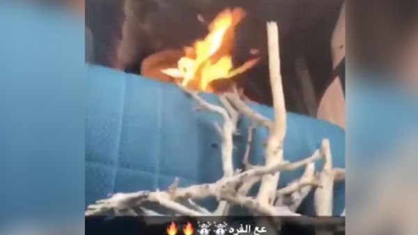 This screengrab from a video shows fire burning inside a container in a car while a Saudi man drives his vehicle. (YouTube/Al-Arabiya)