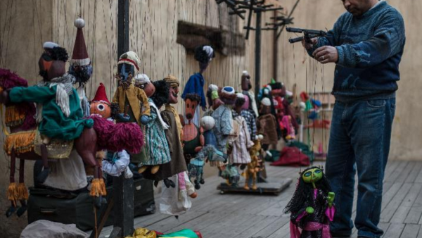 Puppeteer Khaled Essa arranges a string puppet at backstage prior to an open-air show for World Heritage Day in the old town of Cairo. (News.xinhuanet.com)