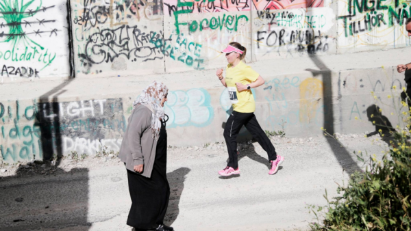 A runner passes the Wall while participating in the Bethlehem Marathon (Facebook / Right to Movement)