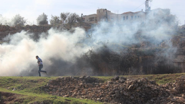 A Palestinian man runs away from tear gas canisters fired by Israeli soldiers during a protest outside Ofer Prison near Ramallah. (image: Hunter Stuart/Al Bawaba) 