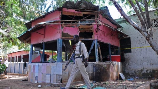 A Somali policeman walks at the scene of an explosion at the Village Restaurant in Mogadishu, on January 2, 2016. (AFP/Mohamed Abdiwahab)