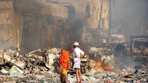 A man and woman look at the damages on the site of the explosion of a truck bomb in the centre of Mogadishu, on October 14, 2017 (Mohamed Abdiwahab/AFP)