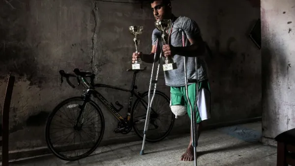 Palestinian cyclist Alaa Al-Daly, 21, who lost his leg by a bullet fired by Israeli troops along the Gaza border during a protest, stands next to his bicycle holding trophies he has won in competitions, at his home in Rafah in the southern Gaza Strip on April 19, 2018. Daly's dream of competing for Palestine at the Asian Games has been shattered after the athletes right leg was amputated after being shot by Israeli soldiers during recent demonstrations in Gaza.
SAID KHATIB / AFP