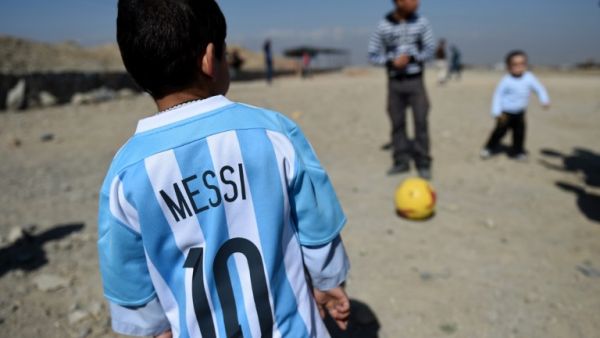 Afghan boy five-year-old Murtaza Ahmadi (C), a young Lionel Messi fan, plays football as he wears a donated and signed shirt by Messi on a field in Kabul on February 26, 2016. Argentine football star Lionel Messi has sent not one, but two jerseys to the five-year-old Afghan boy who became an Internet sensation last month when he was pictured wearing a plastic bag with "Messi" scrawled on it in marker pen. AFP. AFP PHOTO/WAKIL KOHSAR
WAKIL KOHSAR / AFP