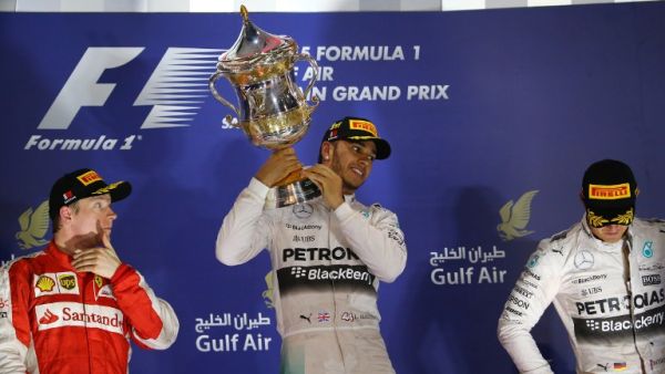Mercedes AMG Petronas British driver Lewis Hamilton (C) hold his winners trophy as he stands on the podium after winning the Formula One Bahrain Grand Prix, ahead of Scuderia Ferrari Finnish driver Kimi Raikkonen (L) in second place and Mercedes AMG Petronas German driver Nico Rosberg (R) in third at the Sakhir circuit in the desert south of the Bahraini capital, Manama, on April 19, 2015. AFP PHOTO / MARWAN NAAMANI
MARWAN NAAMANI / AFP