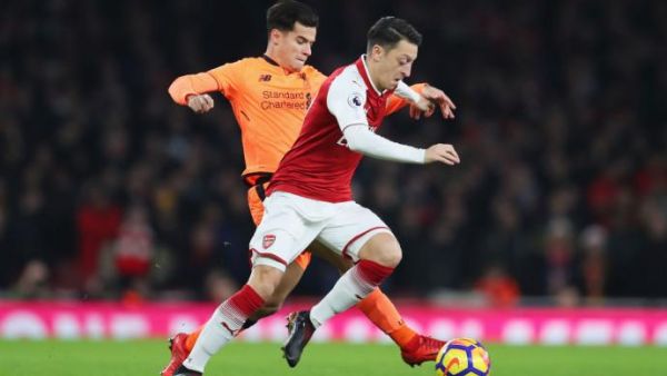 صراع على الكرة بين أوزيل (يمين) وكوتينيو